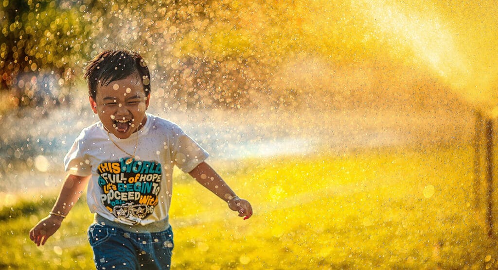 Child running in water smiling.